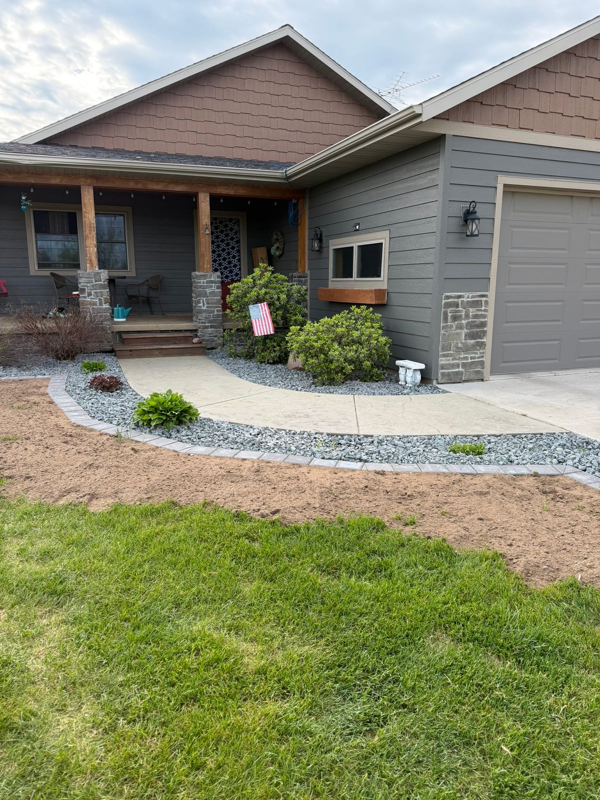 Green lawn in foreground, neat rock bed behind, with house in background